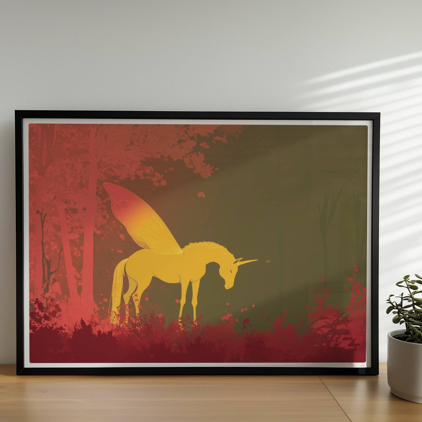 Goldenes Einhorn mit feenhaften Schmetterlingsflügeln steht im roten Märchenwald bei Sonnenaufgang.. Rahmen schwarz 70x50