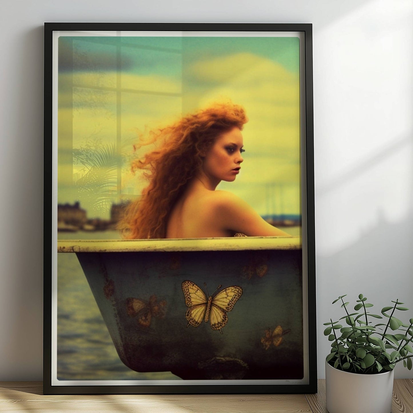 Eine rothaarige Frau sitzt verträumt in einer alten Badewanne mit Schmetterlingsmotiven am Wasser, surreal und märchenhaft.. Rahmen schwarz 50x70
