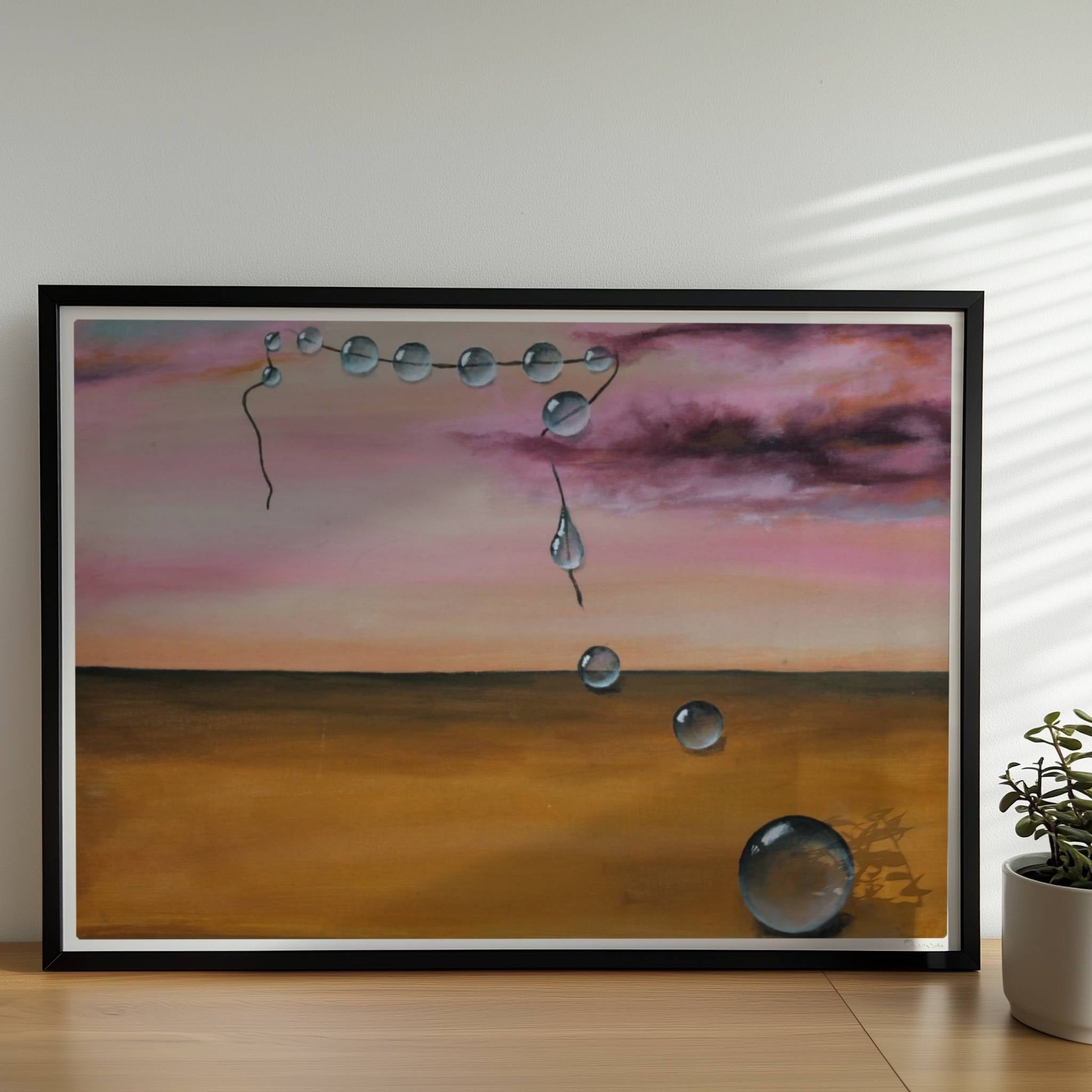 13 schwebende Glastropfen vor rosarotem Himmel über Wüste.. Rahmen schwarz 70x50