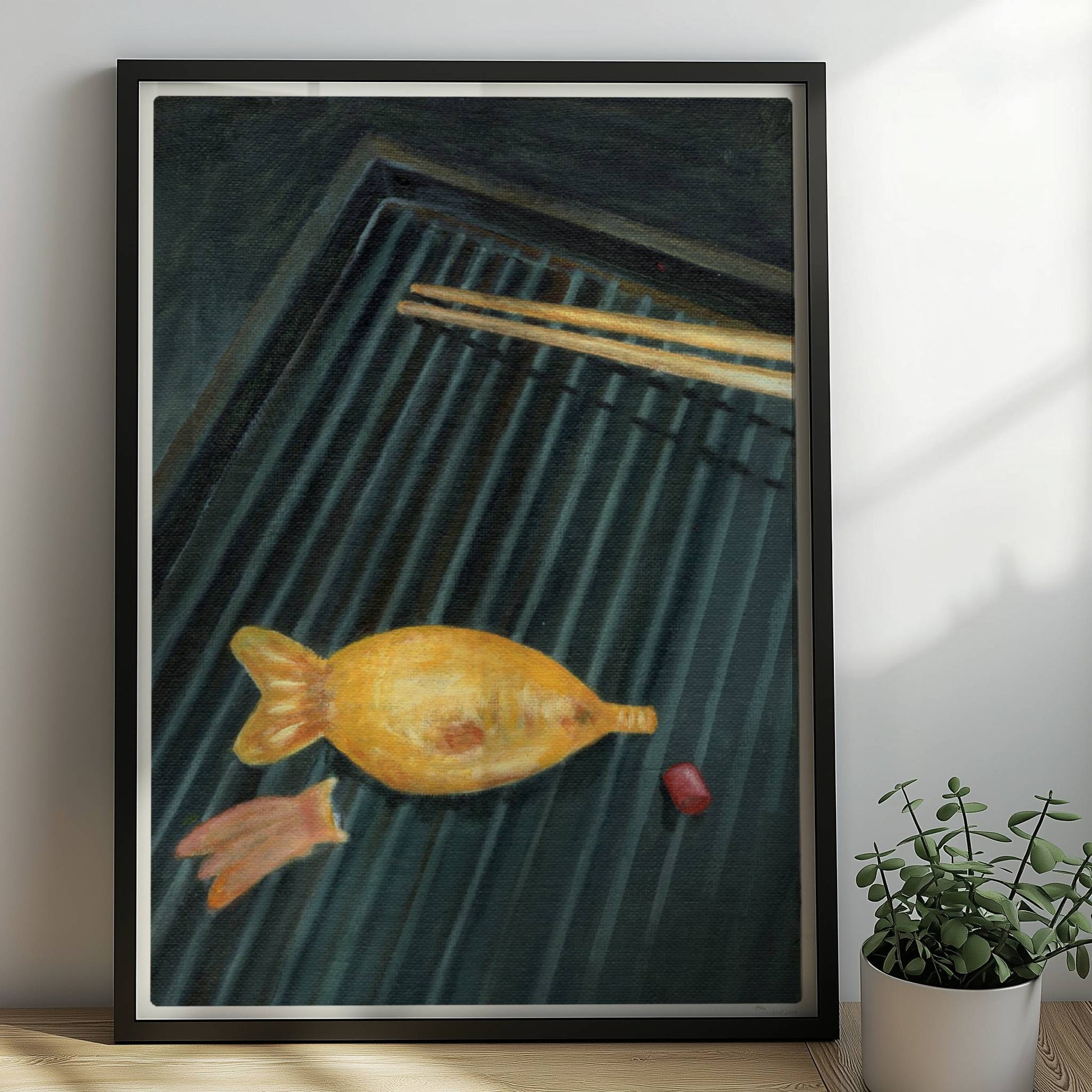 Goldener Fisch auf Sushi-Matte mit Stäbchen, surreal inszeniert.. Rahmen schwarz 50x70