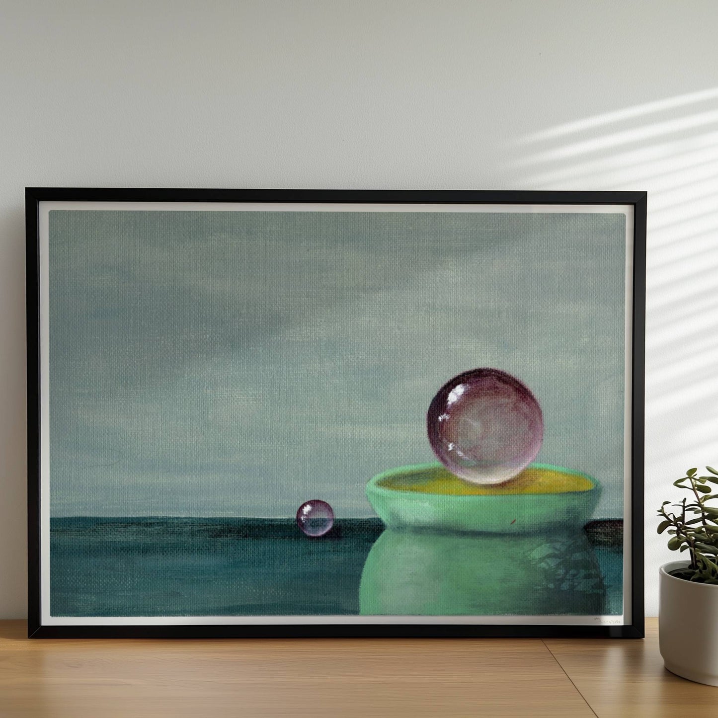 Schwebende Glaskugel über grüner Schale, minimalistische Szene.. Rahmen schwarz 70x50