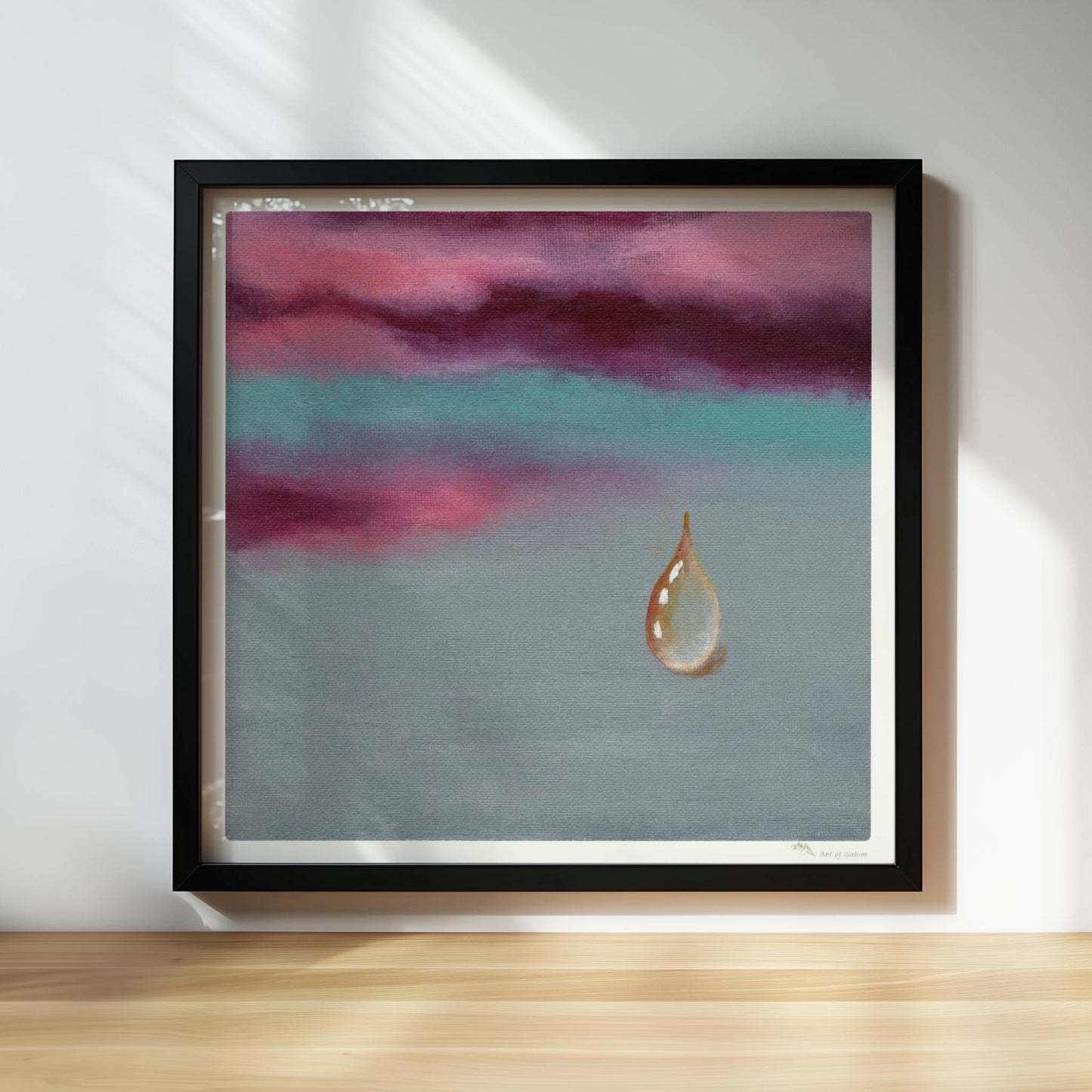 Goldener Tropfen vor dramatischem Himmel in Violett und Türkis.. Rahmen schwarz 30x30