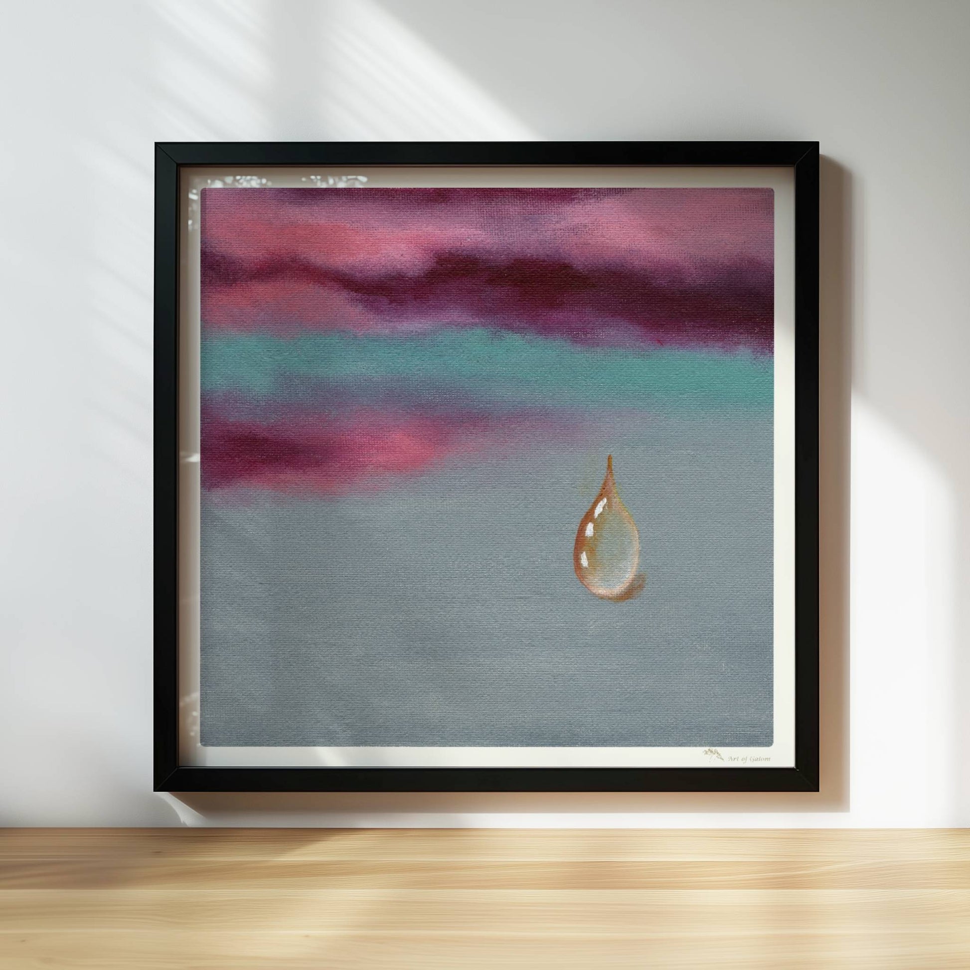 Goldener Tropfen vor dramatischem Himmel in Violett und Türkis.. Rahmen schwarz 30x30