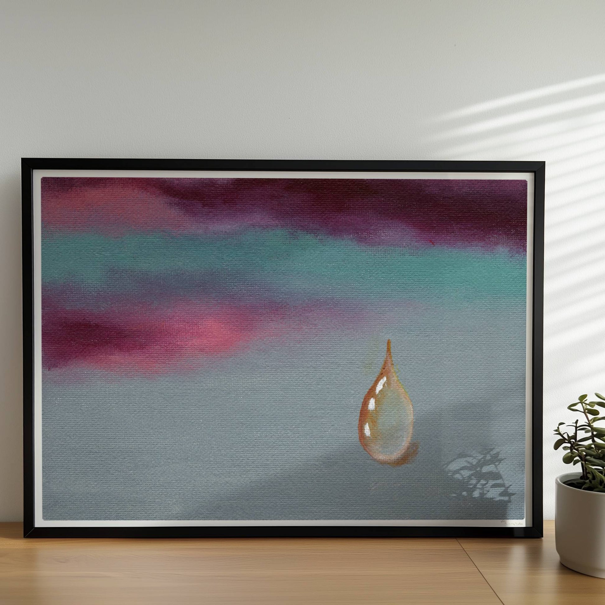 Goldener Tropfen vor dramatischem Himmel in Violett und Türkis.. Rahmen schwarz 70x50