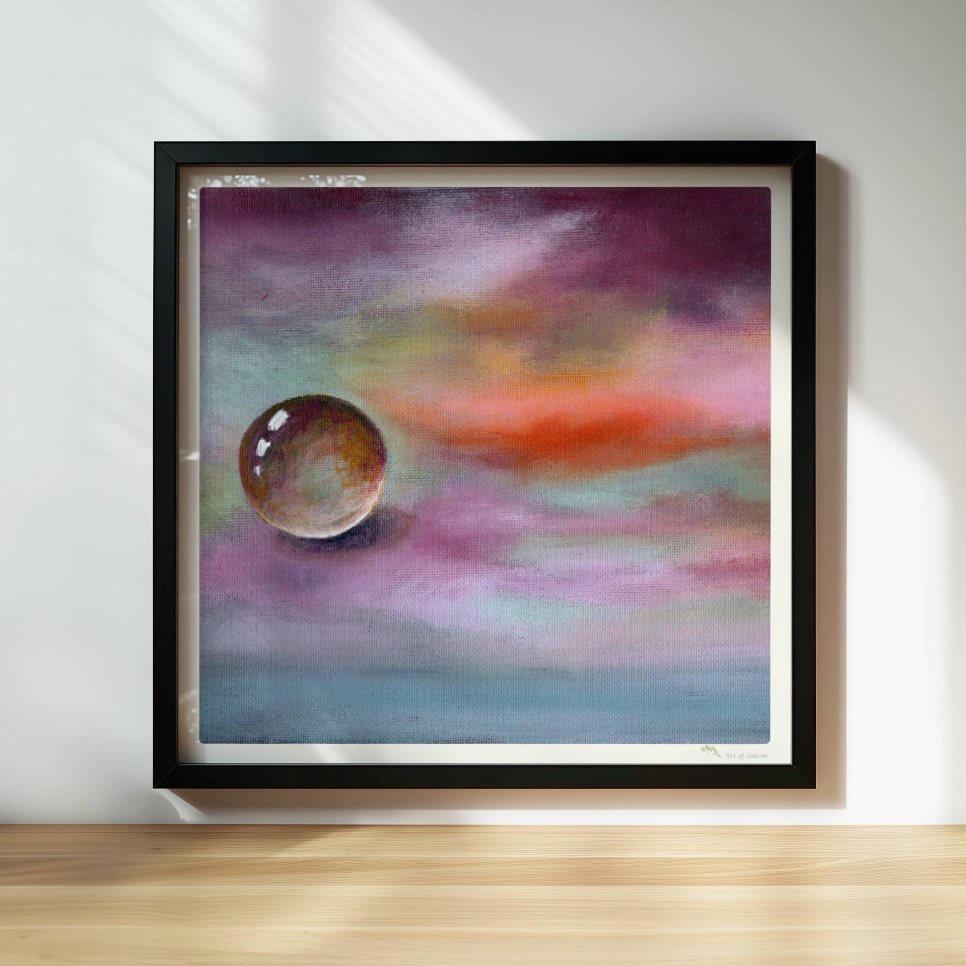 Schwebende Glaskugel vor farbenfrohem Himmel in Lila und Orange.. Rahmen schwarz 30x30