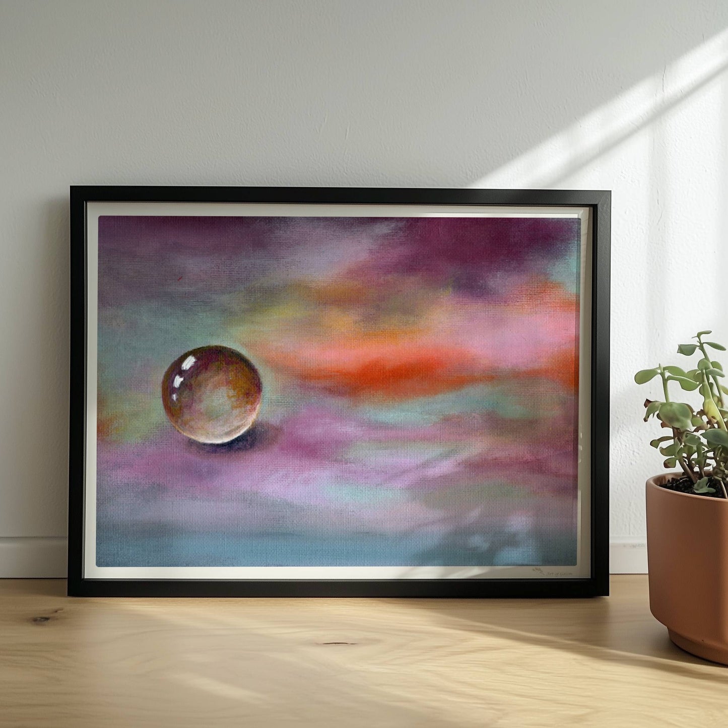 Schwebende Glaskugel vor farbenfrohem Himmel in Lila und Orange.. Rahmen schwarz 40x30