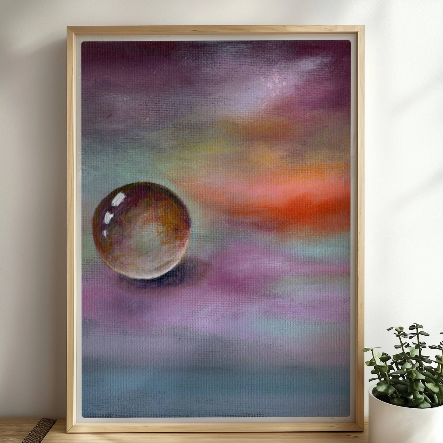 Schwebende Glaskugel vor farbenfrohem Himmel in Lila und Orange.. Rahmen natur 50x70