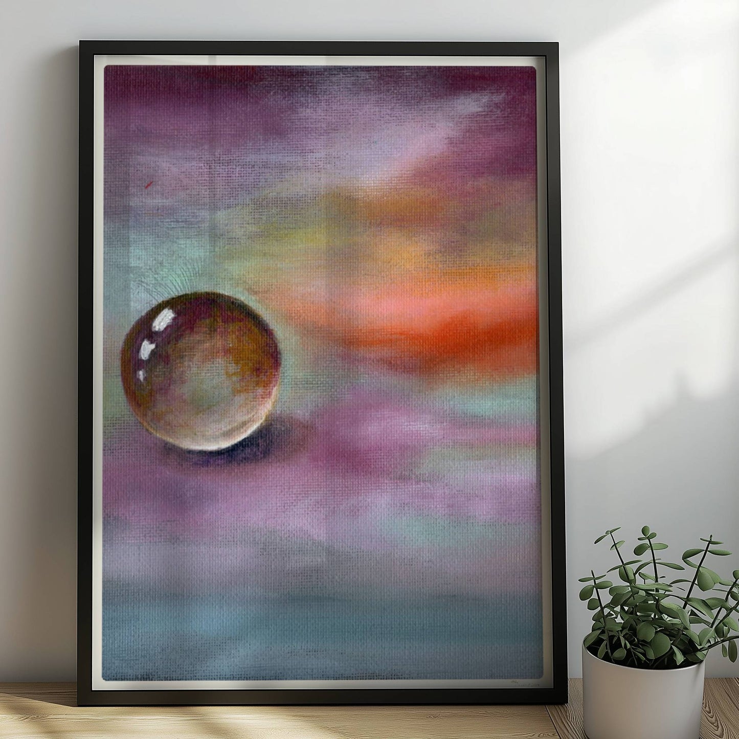 Schwebende Glaskugel vor farbenfrohem Himmel in Lila und Orange.. Rahmen schwarz 50x70